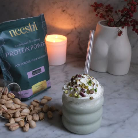 Image of a Pistachio protein shake with a Neeshi protein Pouch and a candle
