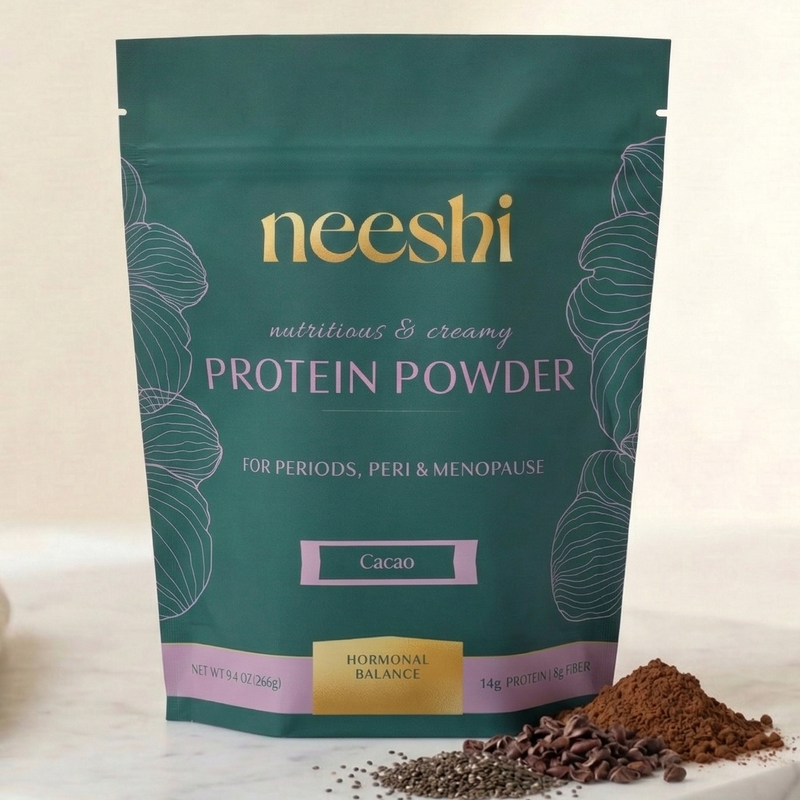 Neeshi protein powder package on a marble surface with cocoa powder.