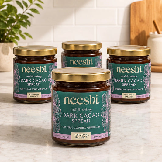 Jar of Neeshi dark cacao spread in a kitchen with a fruit bowl