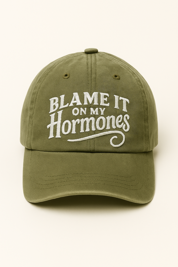 Green cap with 'Blame It On My Hormones' text on a white background