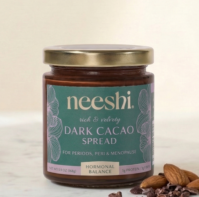 Jar of neeshi dark cacao spread on a marble surface with almonds.